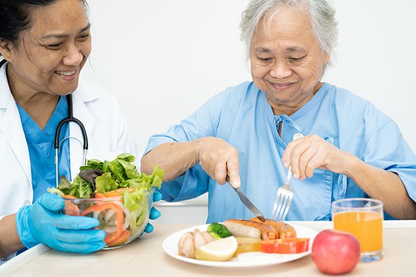 nurse eating with elderly lady 